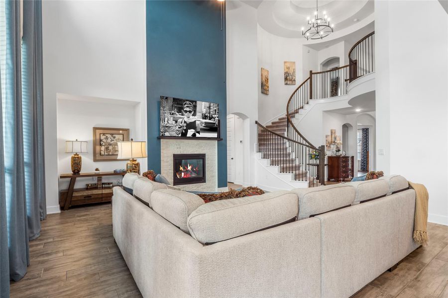 Living area with a fireplace, wood finished floors, a towering ceiling, stairway, and arched walkways Living area with a fireplace, wood finished floors, a towering ceiling, stairway, and arched walkways