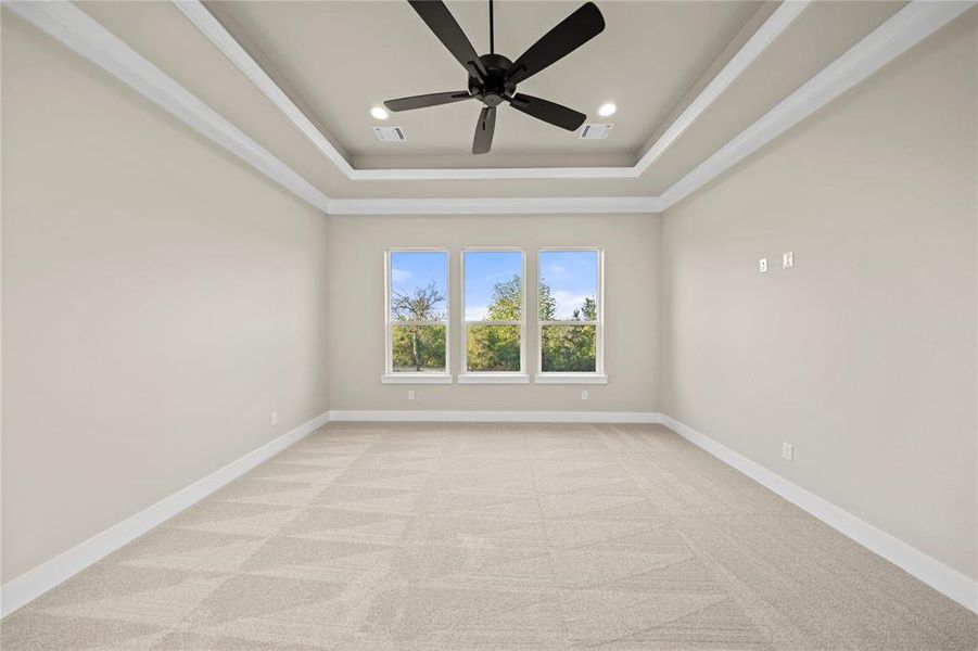 Empty room with light colored carpet, a raised ceiling, recessed lighting, and a ceiling fan