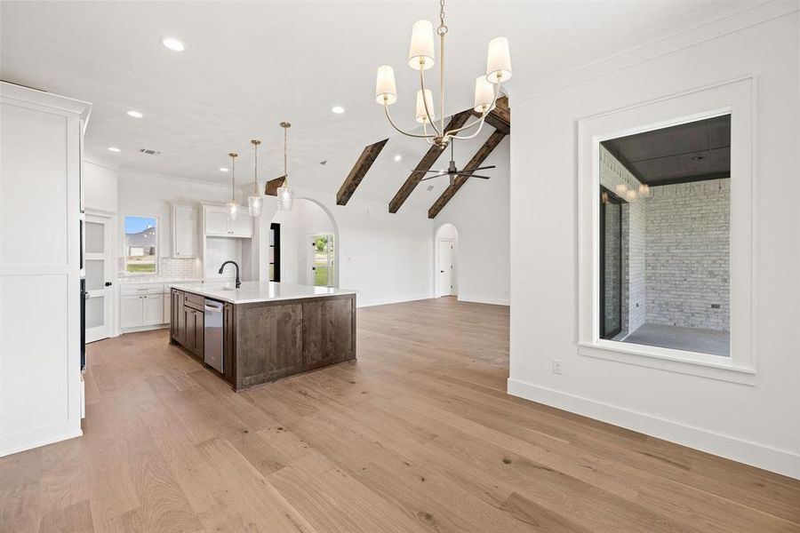 Kitchen with a sink, open floor plan, a kitchen island with sink, arched walkways, and light countertops