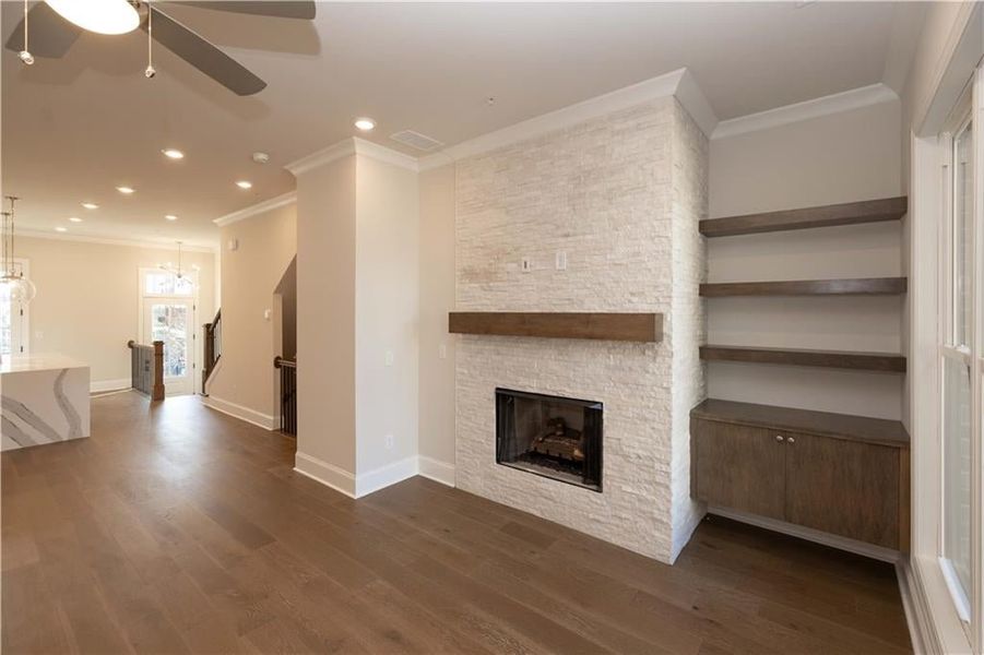Unfurnished living room featuring crown molding, dark wood-style floors, a fireplace, recessed lighting, and a ceiling fan