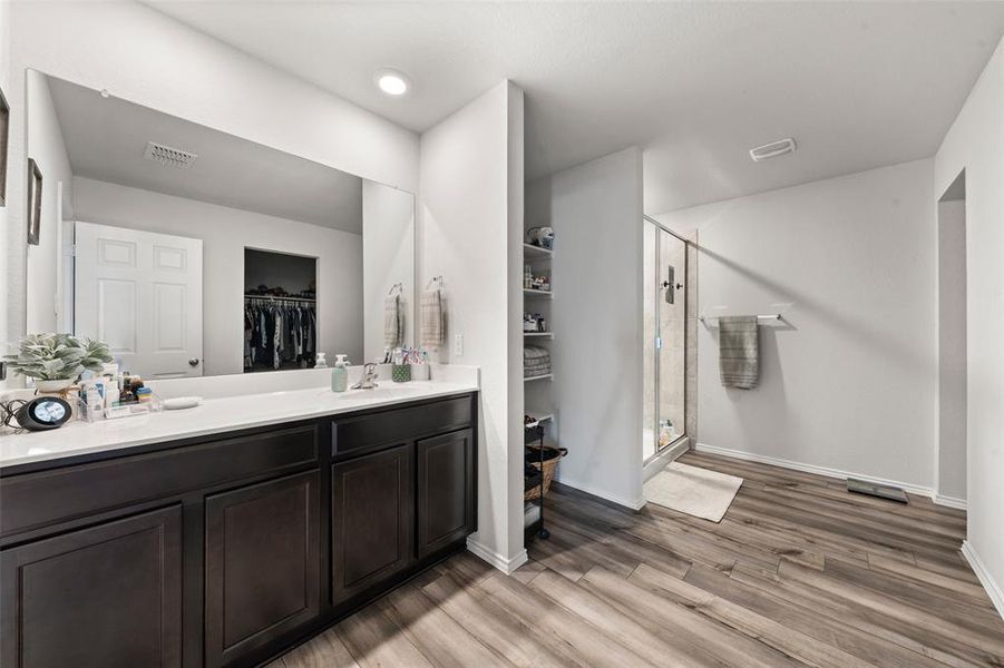 Full bathroom featuring a spacious closet, a stall shower, light wood finished floors, and vanity