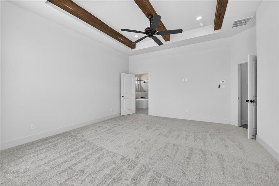Unfurnished bedroom with light carpet, recessed lighting, ceiling fan, a tray ceiling, and ensuite bathroom