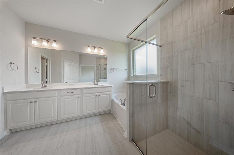 Bathroom with a shower stall, a bath, and double vanity