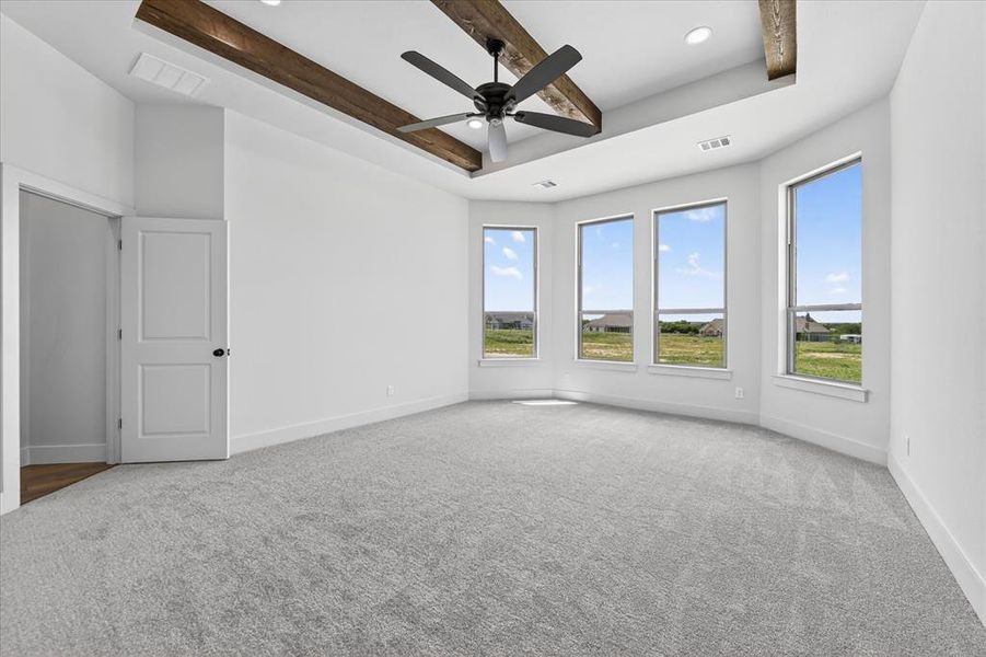 Empty room featuring a raised ceiling, light colored carpet, ceiling fan, and recessed lighting