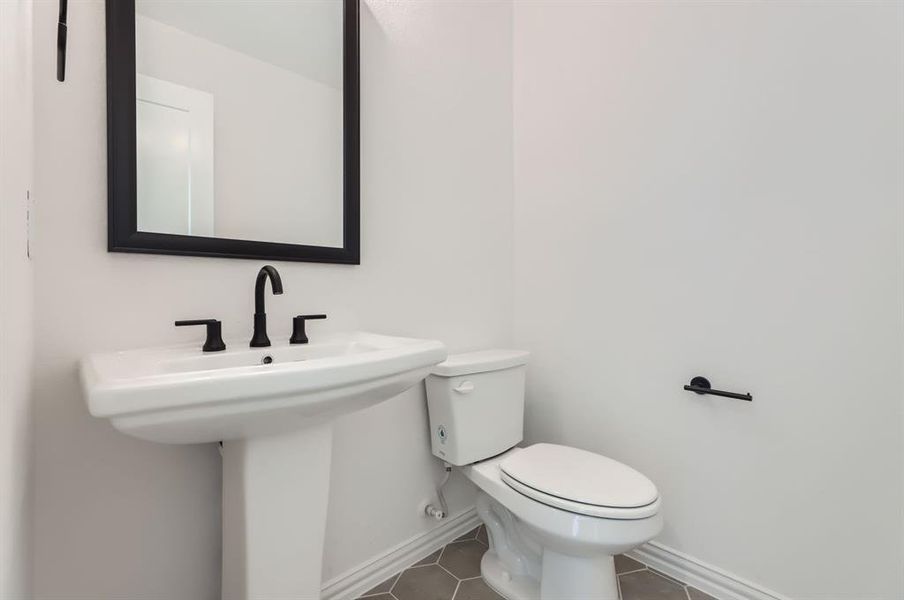 Bathroom featuring toilet, sink, and tile patterned flooring