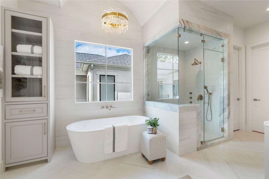 A closer look at the primary shower and 67" Wyndam Mermaid tub. Polished gold fixtures maintain the luxurious feel, coupled with the marble detailing throughout. A handheld sprayer and trio of body jets creates a spa-like feel in your very own home.