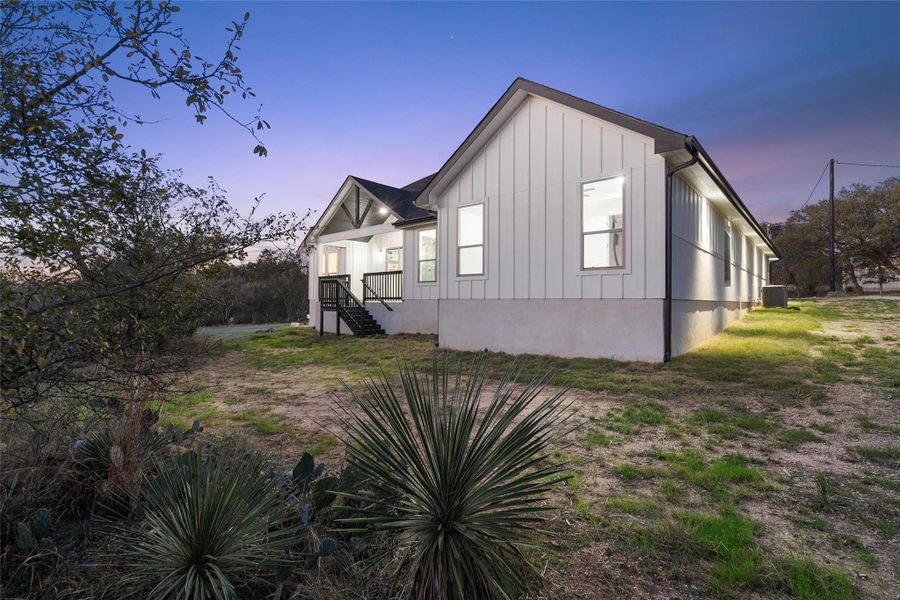 Property exterior at dusk featuring board and batten siding and a yard