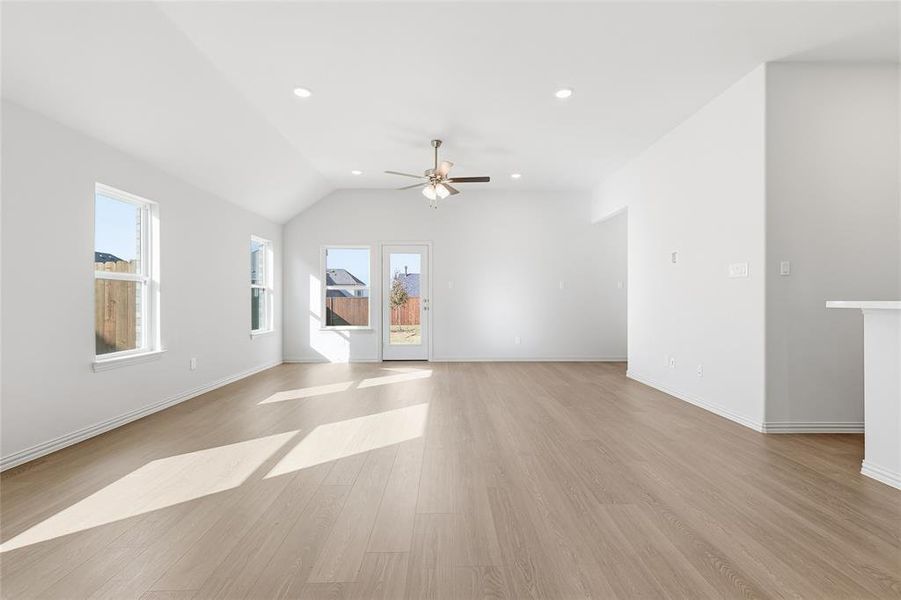Unfurnished room featuring light wood-style floors, lofted ceiling, ceiling fan, and recessed lighting Unfurnished room featuring light wood-style floors, lofted ceiling, ceiling fan, and recessed lighting