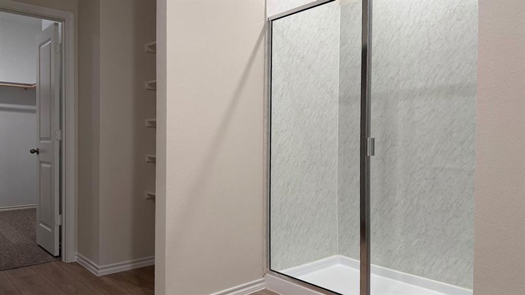 Glass-enclosed shower with a white base and textured wall panels Glass-enclosed shower with a white base and textured wall panels