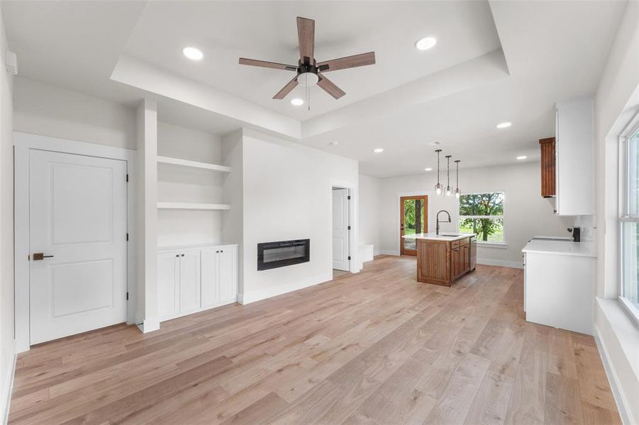 Open-concept living space with light wood-finish flooring, recessed lighting, and a contemporary ceiling fan