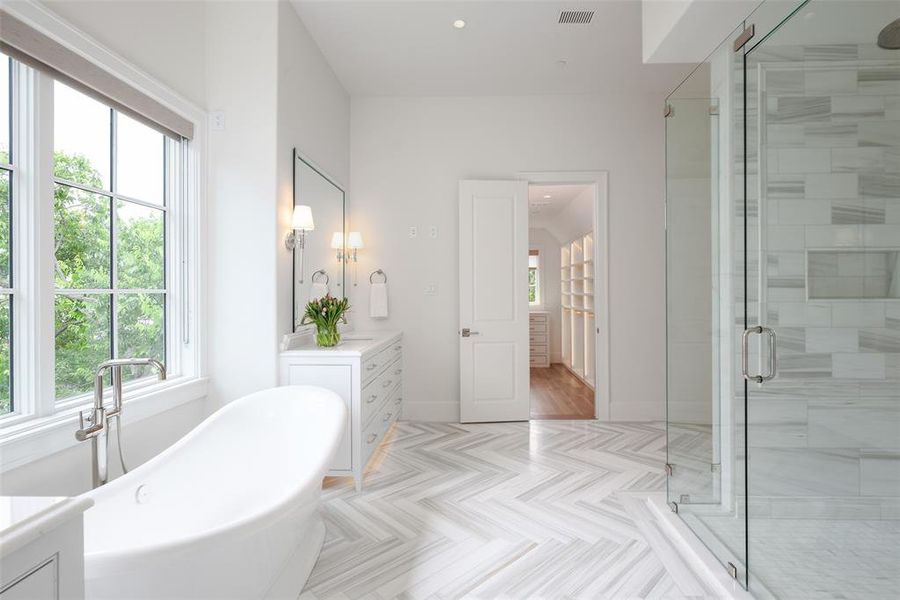 Primary bathroom with dual vanities, stand alone tub, and separate shower