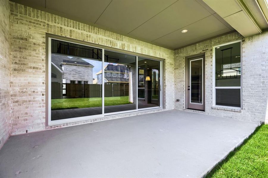 Expansive covered patio featuring a concrete slab, recessed lighting, and brick exterior walls Expansive covered patio featuring a concrete slab, recessed lighting, and brick exterior walls