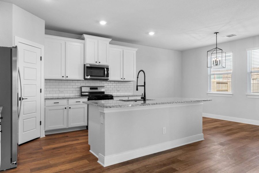 Kitchen with light stone countertops, dark wood finished floors, stainless steel appliances, tasteful backsplash, and a center island with sink