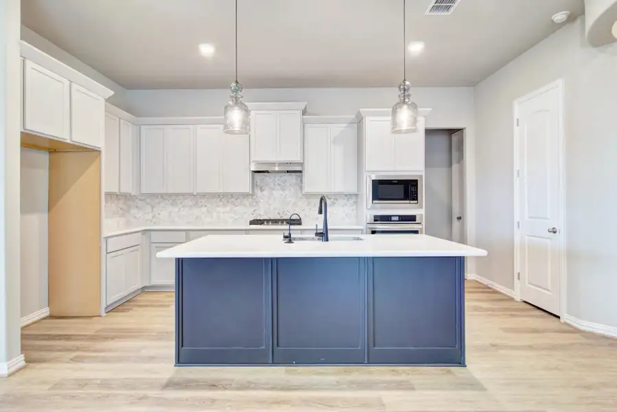 Kitchen featuring white cabinetry, decorative light fixtures, tasteful backsplash, and recessed lighting Kitchen featuring white cabinetry, decorative light fixtures, tasteful backsplash, and recessed lighting