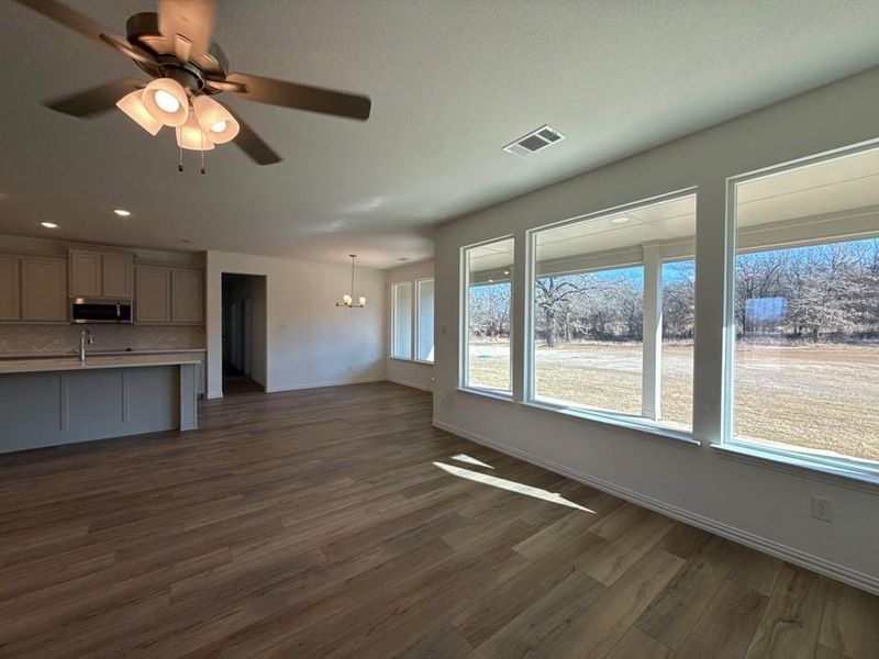 Unfurnished living room with dark wood finished floors, ceiling fan, and a chandelier