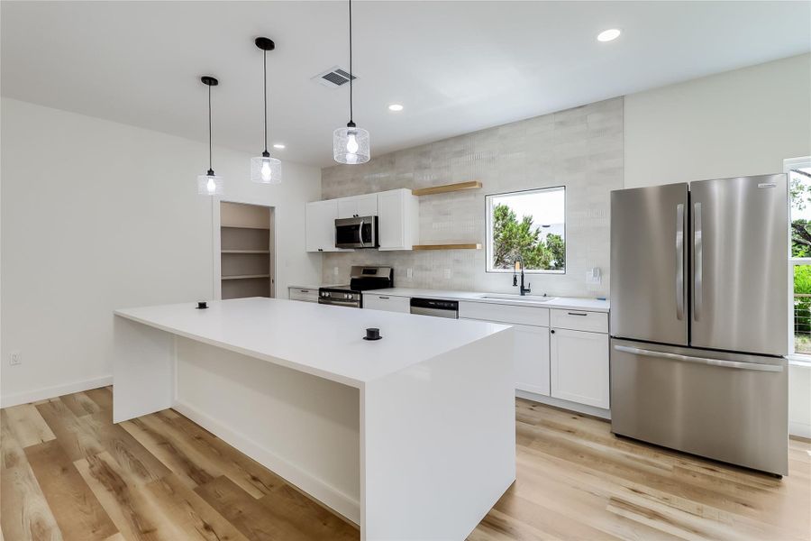 Kitchen with a sink, appliances with stainless steel finishes, white cabinetry and recessed lighting