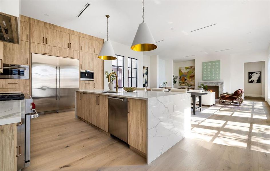 Kitchen featuring light stone countertops, stainless steel appliances, decorative light fixtures, and light wood-style floors Kitchen featuring light stone countertops, stainless steel appliances, decorative light fixtures, and light wood-style floors