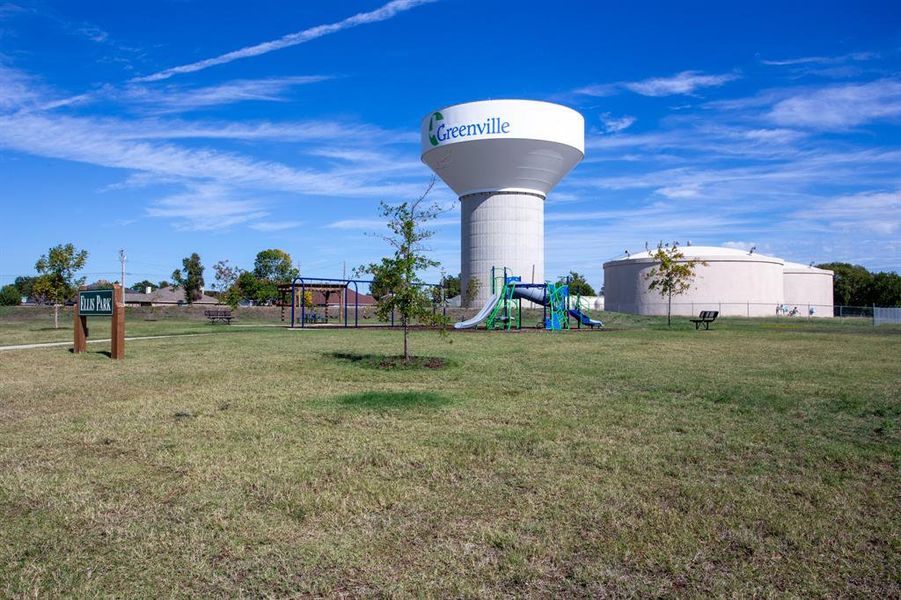 Expansive green space featuring a playground structure with slides and climbing elements