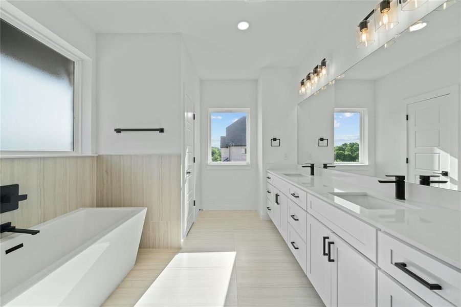 Bathroom featuring double vanity, a freestanding tub, healthy amount of natural light, a wainscoted wall, and recessed lighting Bathroom featuring double vanity, a freestanding tub, healthy amount of natural light, a wainscoted wall, and recessed lighting