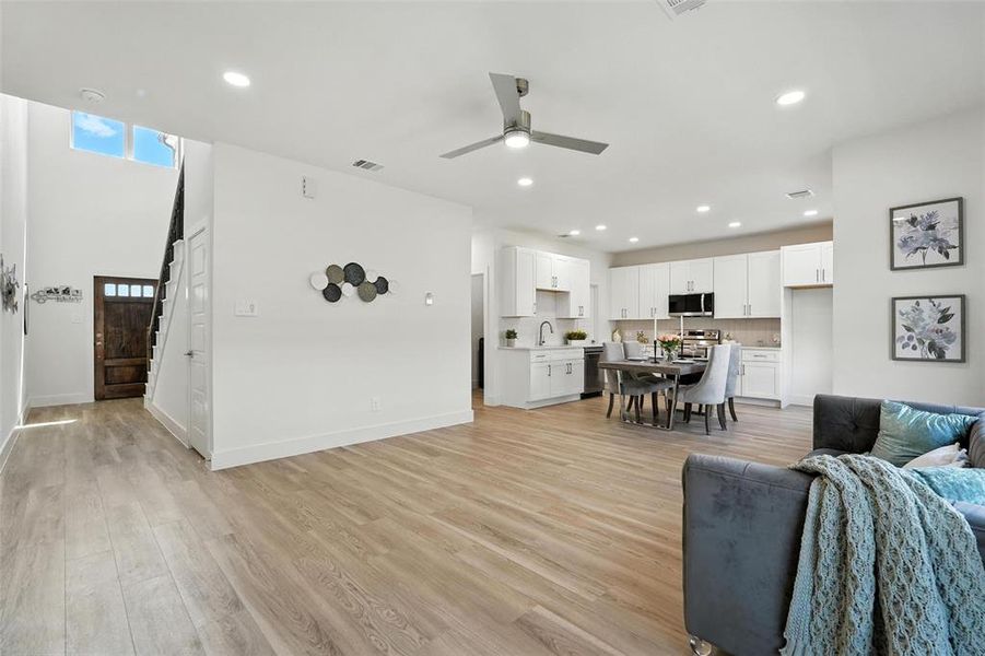 Living room featuring light wood finished floors, recessed lighting, ceiling fan, and stairway