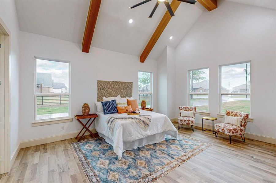 Bedroom with light wood-type flooring, multiple windows, ceiling fan, and beamed ceiling