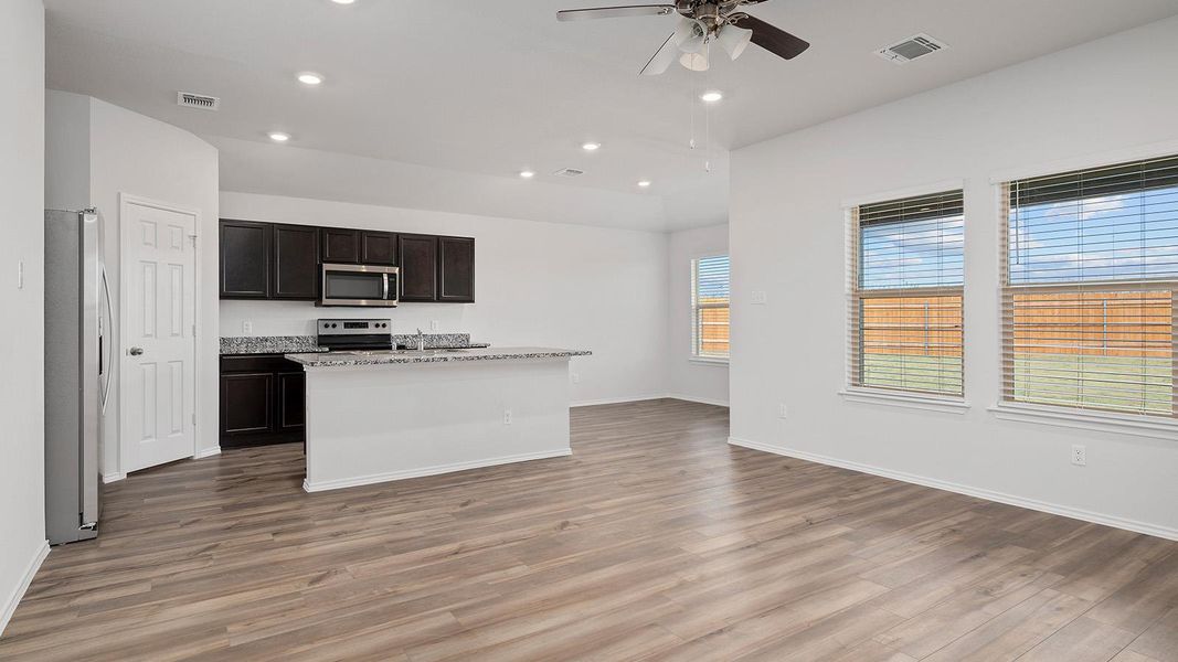 Kitchen with open floor plan, recessed lighting, appliances with stainless steel finishes, a center island with sink, and light wood-style floors