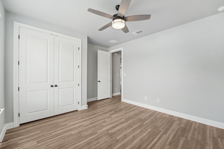 Bedroom 3 with visible vents, a closet, light wood-style floors, baseboards, and ceiling fan