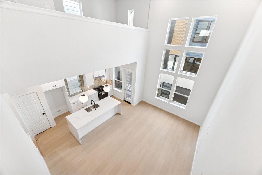 A bird’s-eye view from the ceiling showcases the home’s open-concept layout, highlighting the seamless flow between the kitchen, dining, and living areas, along with the soaring 20-ft ceilings and abundant natural light.
