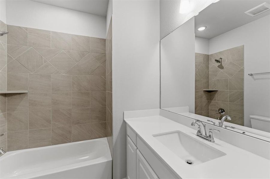 Bathroom featuring a white vanity with an integrated sink, polished chrome faucet, and a large wall-mounted mirror Bathroom featuring a white vanity with an integrated sink, polished chrome faucet, and a large wall-mounted mirror