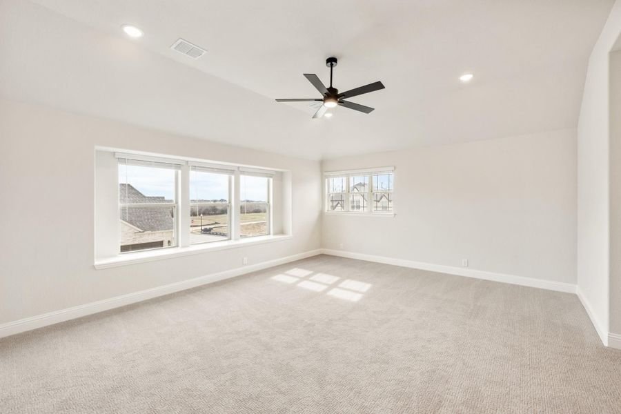 Empty bedroom with carpet flooring, ceiling fan, recessed lighting, and large windows with neighborhood views