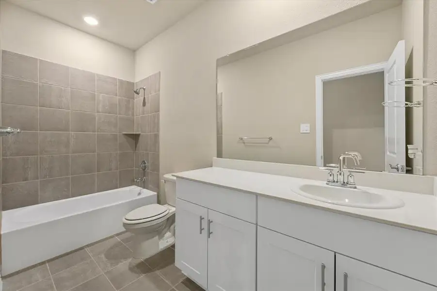 Full bathroom featuring vanity, bathing tub / shower combination, and light tile patterned floors Full bathroom featuring vanity, bathing tub / shower combination, and light tile patterned floors