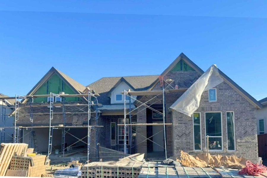 View of front of property with brick siding, a patio area, and a balcony