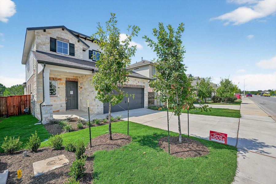 View of front of property with stone siding, concrete driveway, a front lawn, and a garage View of front of property with stone siding, concrete driveway, a front lawn, and a garage