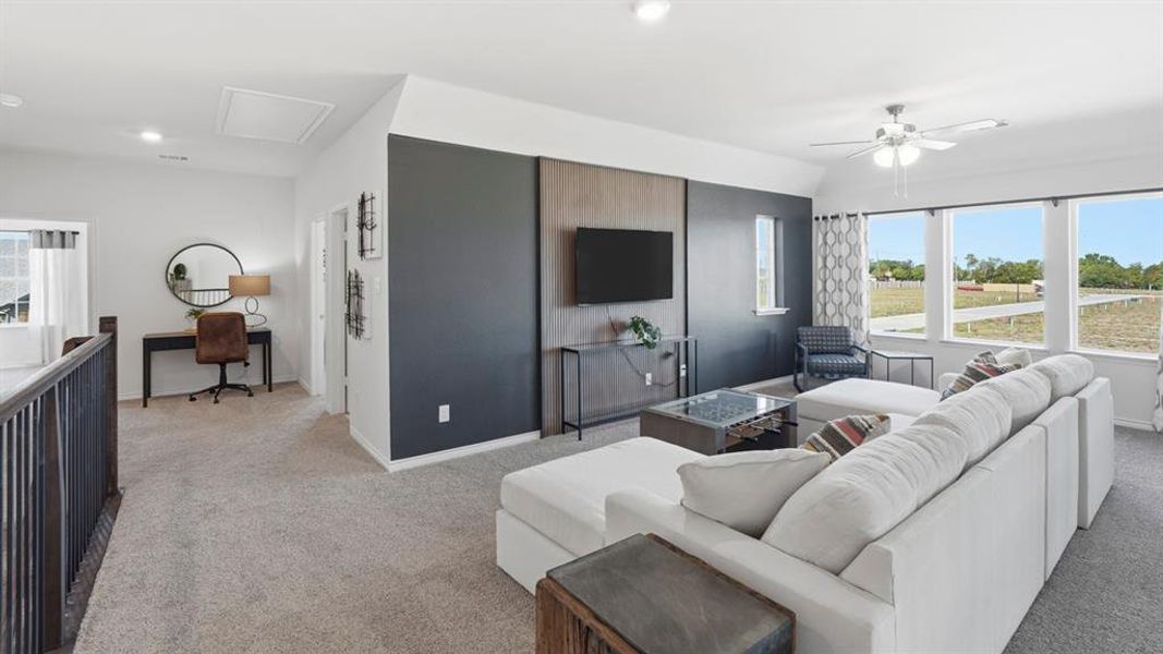 Carpeted open-concept bonus room featuring a media wall with decorative paneling and a ceiling fan Carpeted open-concept bonus room featuring a media wall with decorative paneling and a ceiling fan