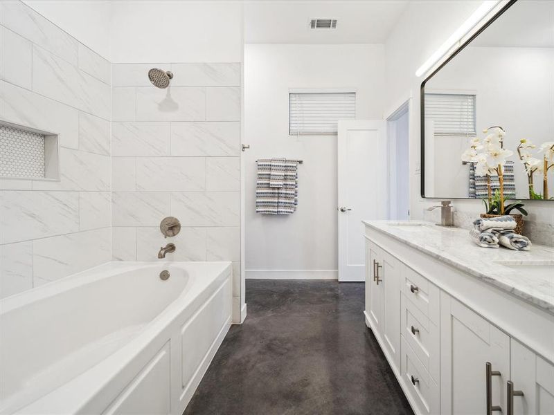 Bathroom featuring vanity, concrete floors, and tiled shower / bath