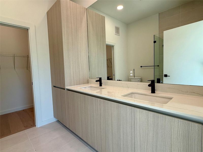 Modern bathroom featuring dual sinks, generous counter space, and a sleek mirror.