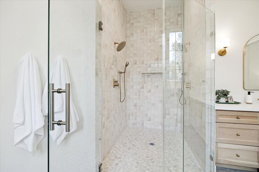 Tile walk-in shower with frameless glass, dual shower heads, and a built-in niche.