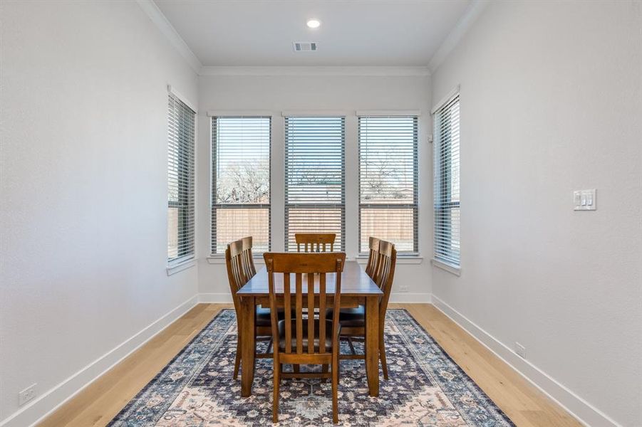 Dining area with a wealth of natural light, hardwood / wood-style floors, and ornamental molding