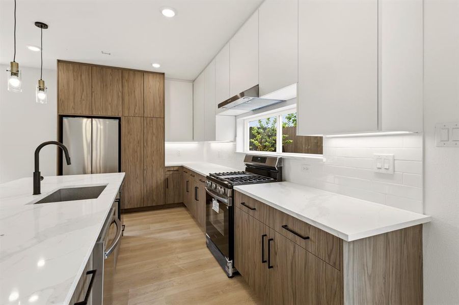 The kitchen features a contemporary design with white upper cabinets and wood-grain lower cabinetry, complemented by white countertops