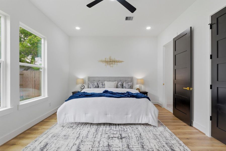 The spacious primary bedroom features continued luxury vinyl flooring, a ceiling fan, and a spa-like en suite with an ample walk-in closet.