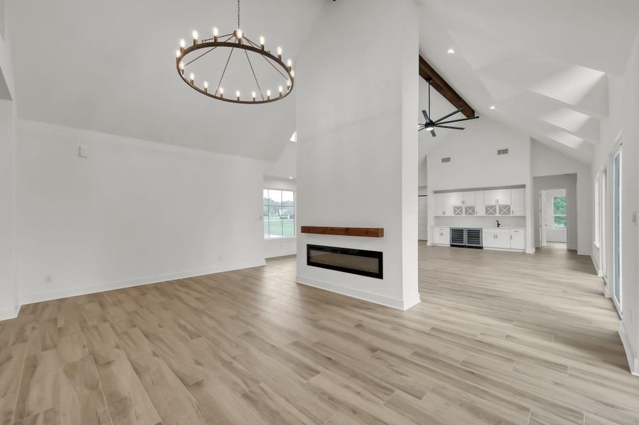 Elegant dining area highlighted by a dramatic chandelier and positioned adjacent to the double-sided fireplace. The open layout seamlessly connects dining, living, and kitchen spaces.