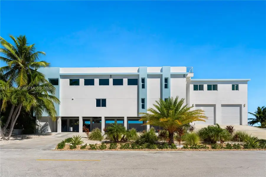 Contemporary multi-level exterior featuring white stucco finish, dual garage bays, expansive windows, and integrated ground-level parking Contemporary multi-level exterior featuring white stucco finish, dual garage bays, expansive windows, and integrated ground-level parking