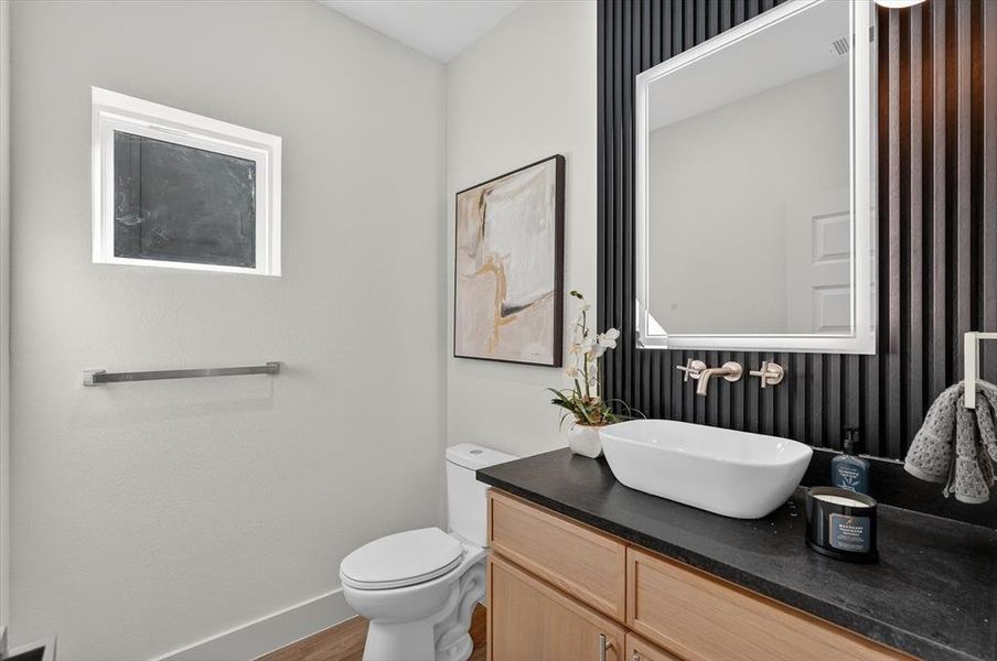 Powder room featuring a vessel sink, wall-mounted faucet, and black slatted accent wall