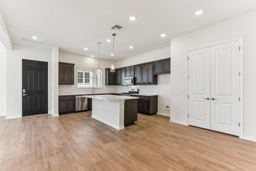 Kitchen with tasteful backsplash, a center island, hanging light fixtures, recessed lighting, and dark brown cabinetry Kitchen with tasteful backsplash, a center island, hanging light fixtures, recessed lighting, and dark brown cabinetry