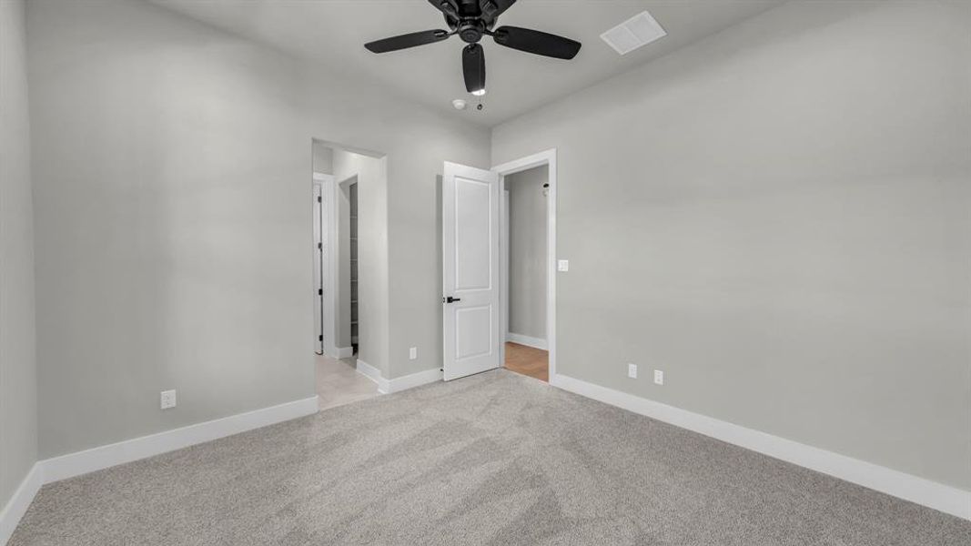 Carpeted room featuring a ceiling fan with black blades, vaulted ceiling, and white baseboards
