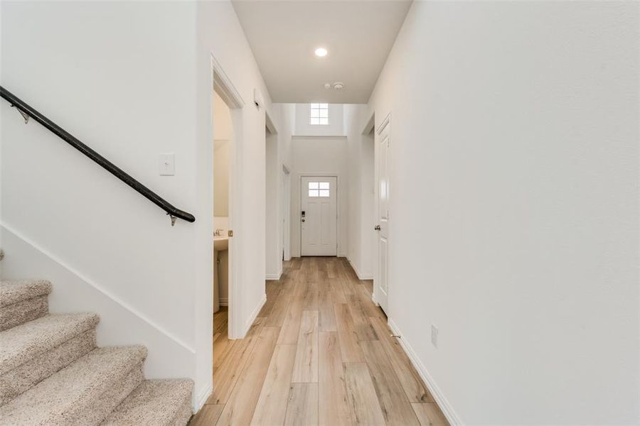 Doorway featuring a towering ceiling and light wood-type flooring