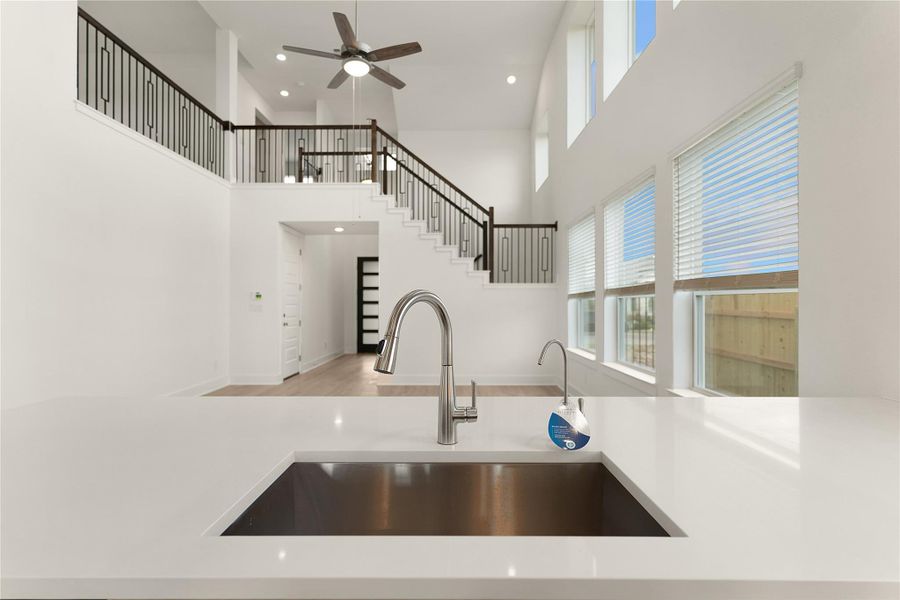 Kitchen featuring a towering ceiling, wood finished floors, a ceiling fan, plenty of natural light, and light countertops