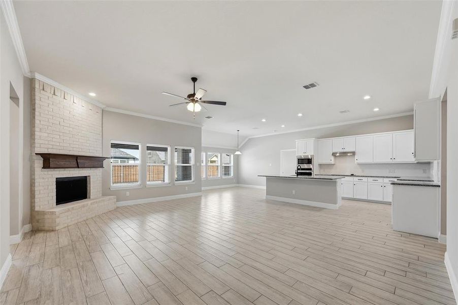 Unfurnished living room featuring ornamental molding, a brick fireplace, ceiling fan, wood finish floors, and recessed lighting Unfurnished living room featuring ornamental molding, a brick fireplace, ceiling fan, wood finish floors, and recessed lighting
