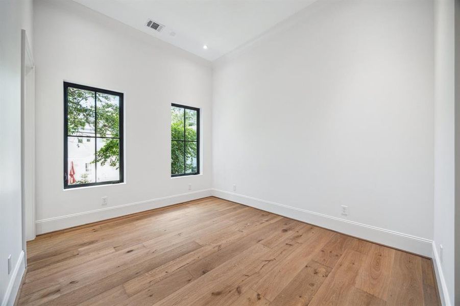 The first of four secondary bedrooms features European white oak flooring, a spacious walk-in closet, and a private ensuite bathroom. With a designer ceiling fan and bright Western exposures, the room is filled with natural light, offering both comfort and style.