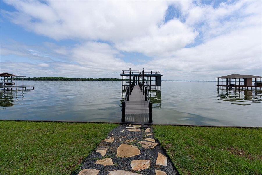 Dock area featuring boat lift, a water view, and a yard
